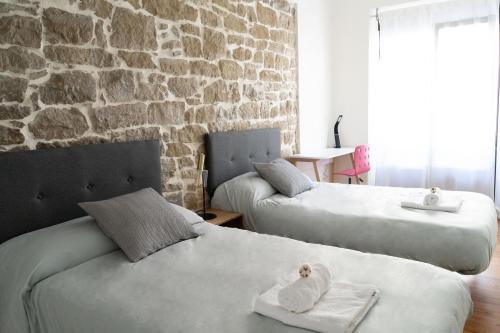 two beds in a room with a brick wall at Entre Algodones in Logroño
