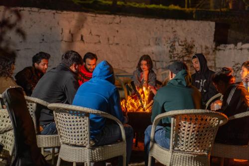 a group of people sitting around a fire at Hill River Resort - Central Heated & Air Cooled - Near Mall Road , Best Property of Manali 2024- 2025 in Manāli