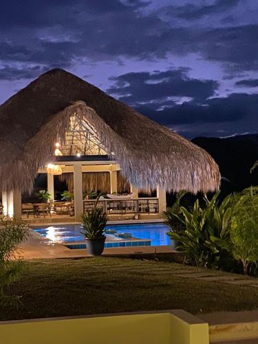 a resort with a pool and a straw roof at Selva Serena in Anapoima