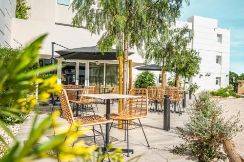 an outdoor patio with a table and chairs at Greet hôtel Montpellier Aéroport Parc des Expos in Mauguio