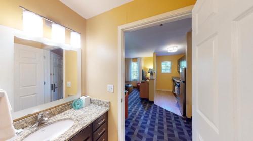 a bathroom with a sink and a mirror and a hallway at Residences at Tewksbury in Tewksbury