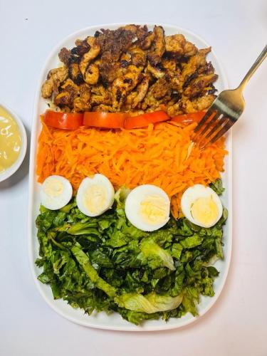 a plate of food with eggs and vegetables with a fork at The Tranquil Mews in Abuja