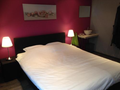 a bedroom with a large white bed with two lamps at Vrije Vlinders in IJzendijke