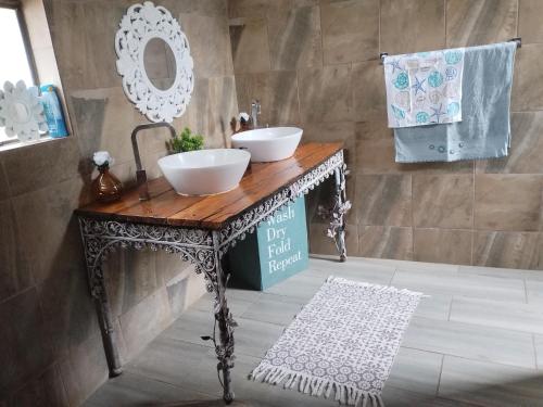 baño con 2 lavabos sobre una mesa de madera en casa bella, en Hartbeespoort