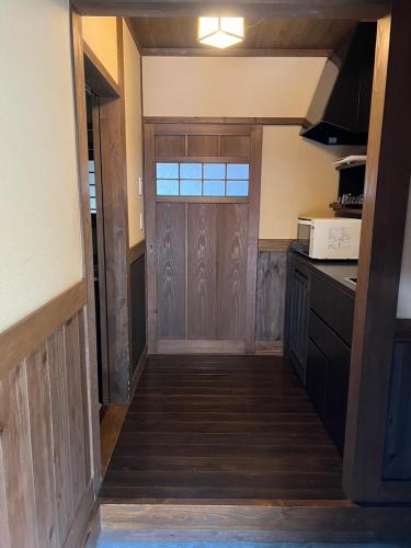 a hallway leading to a kitchen with a wooden door at 御宿だいこんや in Takamori
