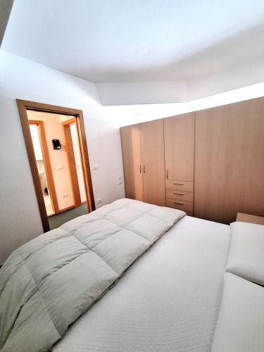 a bedroom with a large bed and a mirror at Appartamenti Vacanze Casa -Residence Albare - check in Vacanze Casa - Marilleva 900 in Marilleva