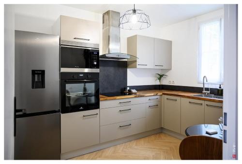 une cuisine avec des armoires blanches et des appareils en acier inoxydable dans l'établissement Élégante maison entre Paris et Disney avec parking, à Bailly-Romainvilliers