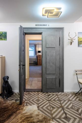 a black dog sitting in front of a door at CHATA LESOVNA in Pec pod Sněžkou
