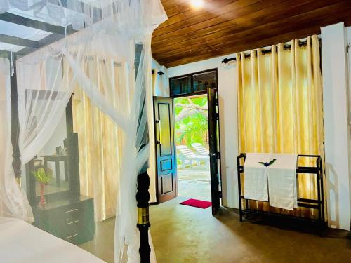a bedroom with a bed and an open door at Maritime Nest Cabanas in Tangalle