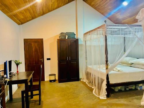 a bedroom with a canopy bed and a desk at Maritime Nest Cabanas in Tangalle