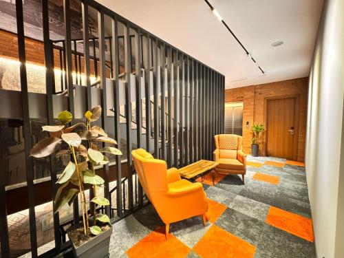 an office lobby with orange chairs and a plant at Tsalamuri Old Tbilisi in Tbilisi City