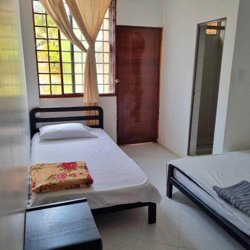 a bedroom with two beds and a window and a door at Hotel Iloa in Pitalito