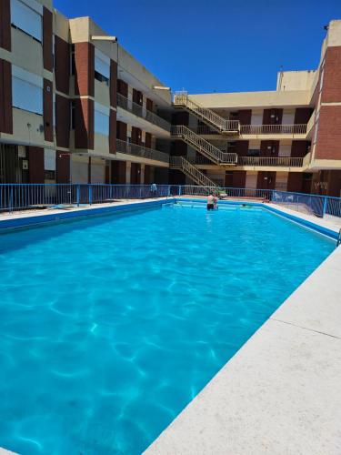 une grande piscine devant un immeuble dans l'établissement Cálido Loft con pileta cerca del centro., à Villa Carlos Paz