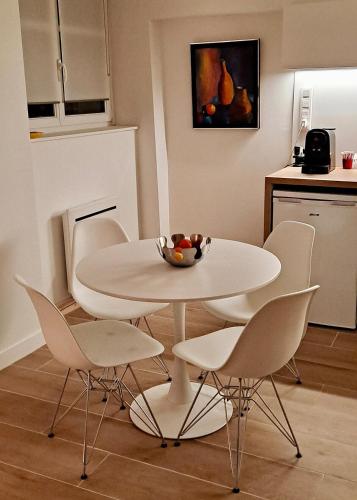- une table à manger blanche avec des chaises et une corbeille de fruits dans l'établissement La Tour - Au Coeur de Langres, à Langres