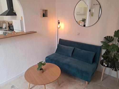 a living room with a blue couch and a table at Cosy studio proche à 30min des plages in Murviel