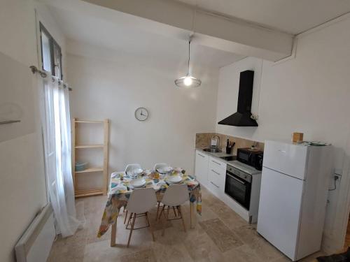 Il comprend une cuisine équipée d'une table avec des chaises et d'un réfrigérateur blanc. dans l'établissement Cosy studio proche à 30min des plages, à Murviel