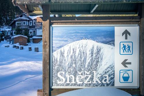 a sign for a ski resort with a snow covered mountain at CHATA LESOVNA in Pec pod Sněžkou