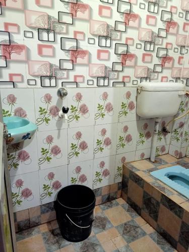 a bathroom with a toilet and a sink with flowers on the wall at Paribartan Hotel & Lodge in Farakka