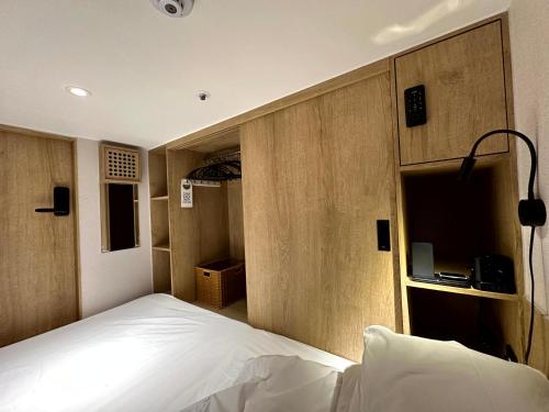 a bedroom with a white bed and wooden walls at Nomad Live Hostel in Busan