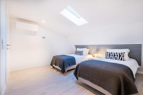 two beds in a room with white walls and wood floors at Old Town Charm Apartment in Albufeira
