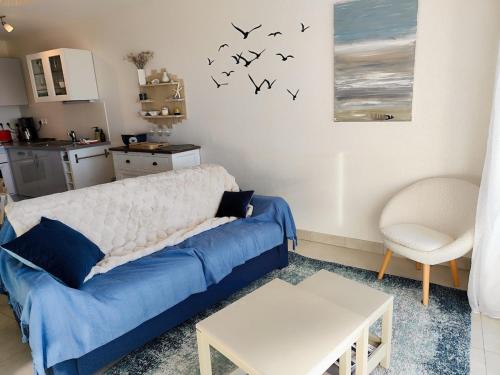 a living room with a blue couch and birds on the wall at Vue baie à l'infini in Le Crotoy