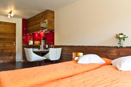 ツェルマットにあるStudio Castor Zermattのベッドルーム1室(ベッド2台付)、赤い壁のキッチン
