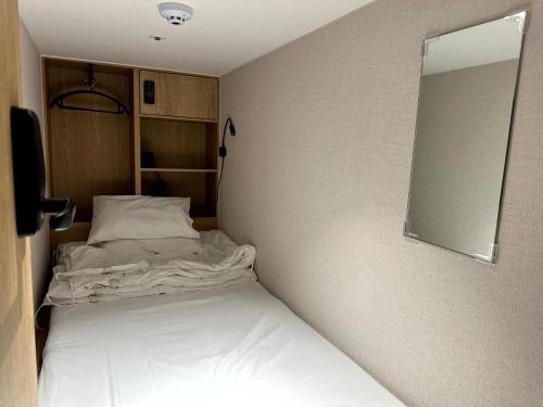 a small bedroom with a bed and a mirror at Nomad Live Hostel in Busan