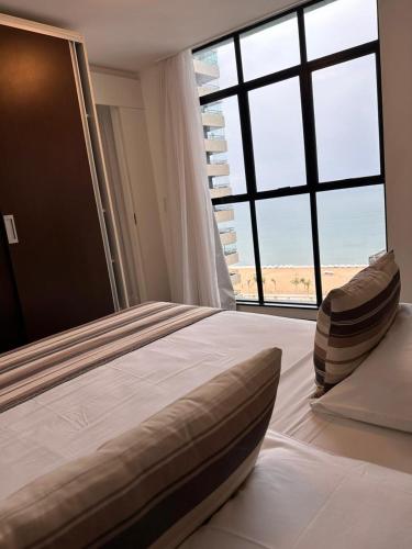 a bedroom with a large bed with a large window at Hotel Brasil Tropical in Fortaleza