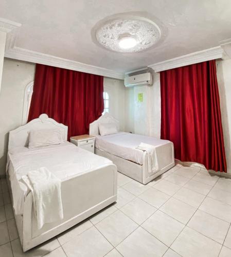 two beds in a room with red curtains at Falcon heaven in 6th Of October