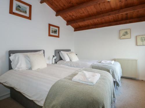 deux lits jumeaux dans une chambre aux murs blancs dans l'établissement Seafarer's Haven, à Porthmadog