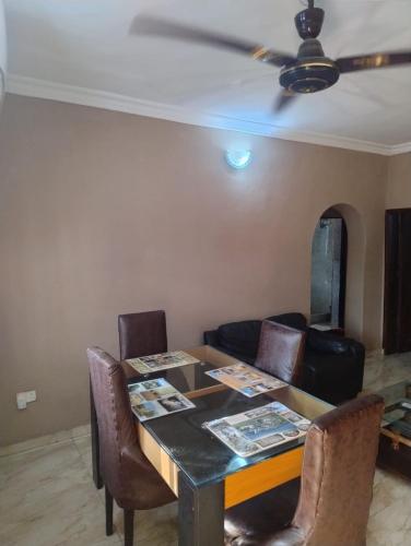 a dining room table with chairs and a ceiling fan at The Homely Hideout in Alakuko