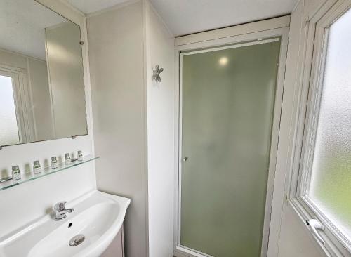 un bagno con doccia, lavandino e specchio di Loc younes a Litteau