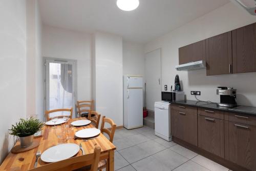 une cuisine avec une table en bois avec des chaises et une cuisine avec un réfrigérateur dans l'établissement LE BACHUT - CHALAMONT proche PEROUGES, à Chalamont