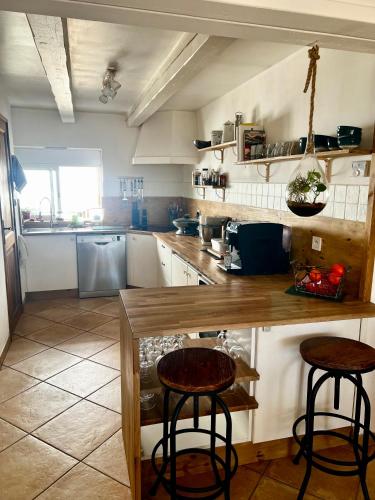 - une cuisine avec un comptoir et deux tabourets dans l'établissement Jolie maison chaleureuse, à Sainte-Tulle