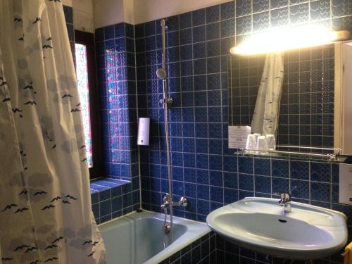 a blue tiled bathroom with a sink and a tub at Hotel Union in Sarreguemines