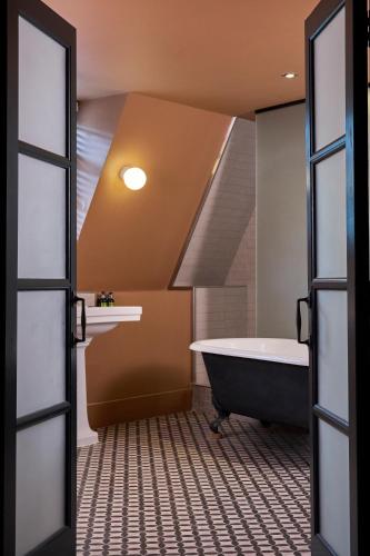 an attic bathroom with a tub and a sink at Hotel du Vin Bristol in Bristol