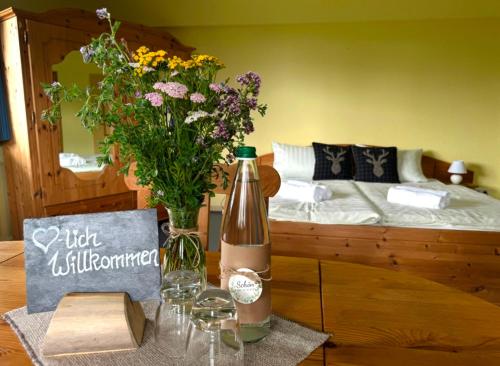 a bottle of wine sitting on a table with flowers at Charlottenhaus in Kühndorf
