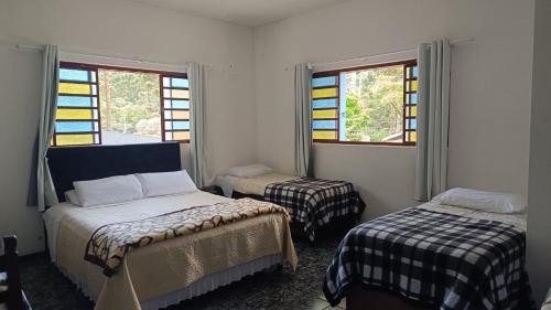 a bedroom with two beds and stained glass windows at A Nossa Casinha no Bosque - 4min do Parque Capivari in Campos do Jordão