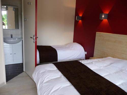 um quarto de hotel com duas camas e um lavatório em La Godinière em Cholet