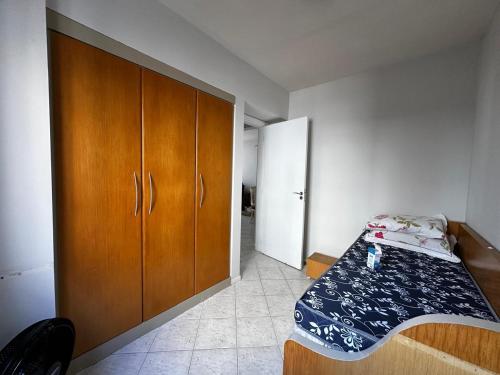 a bedroom with a bed and a wooden cabinet at APT ALUGUEL Praia central in Balneário Camboriú