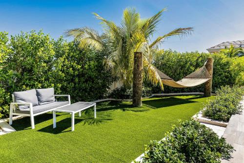 a hammock and a chair in a garden with a palm tree at Romantic Escape, Walk to Beach, Pool, Hammock in Long Bay Hills