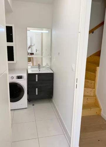 une cuisine blanche avec un évier et un micro-ondes dans l'établissement Maisonnette au portes du Pyla, à La Teste-de-Buch