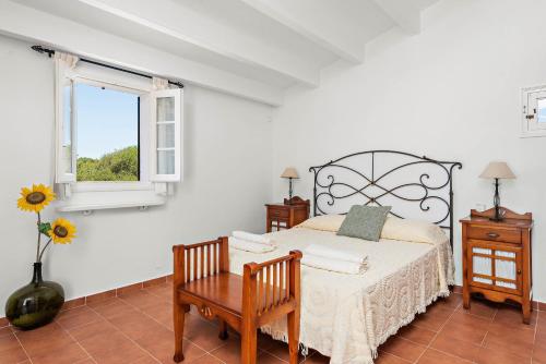 a bedroom with a bed and a table and a window at Casa Nova de Biniparrell in Sant Lluis