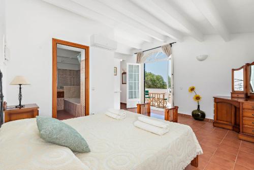 a white bedroom with a bed and a mirror at Casa Nova de Biniparrell in Sant Lluis