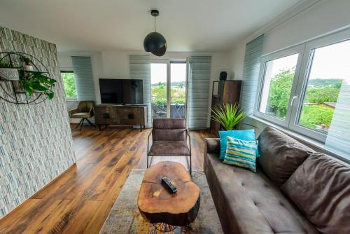 a living room with a brown leather couch and a table at Charming Loft Ferienwohnung Bodensee in Meckenbeuren