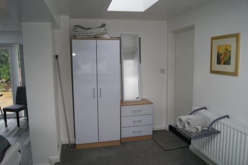 a room with a white cabinet and a chair at Modern Retreat Near Town & Nature with Stunning Views Entertainment and Parking in Burton upon Trent