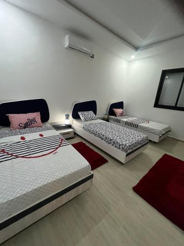 three beds in a room with red rugs at Villa Léann in Mezraya