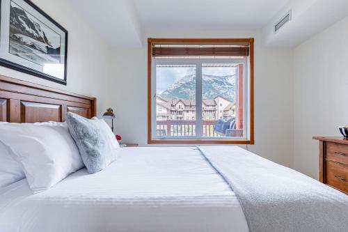 a bedroom with a large white bed and a window at Mountain Paradise at Falcon Crest Lodge in Canmore