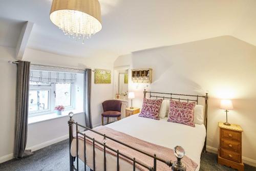 Schlafzimmer mit einem Bett, einem Fenster und einem Kronleuchter in der Unterkunft Host & Stay - Anvil Cottage in Kirkbymoorside