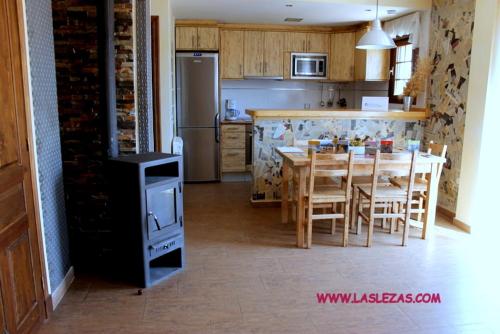 cocina con mesa, sillas y nevera en Casa Rural Las Lezas, en Biel